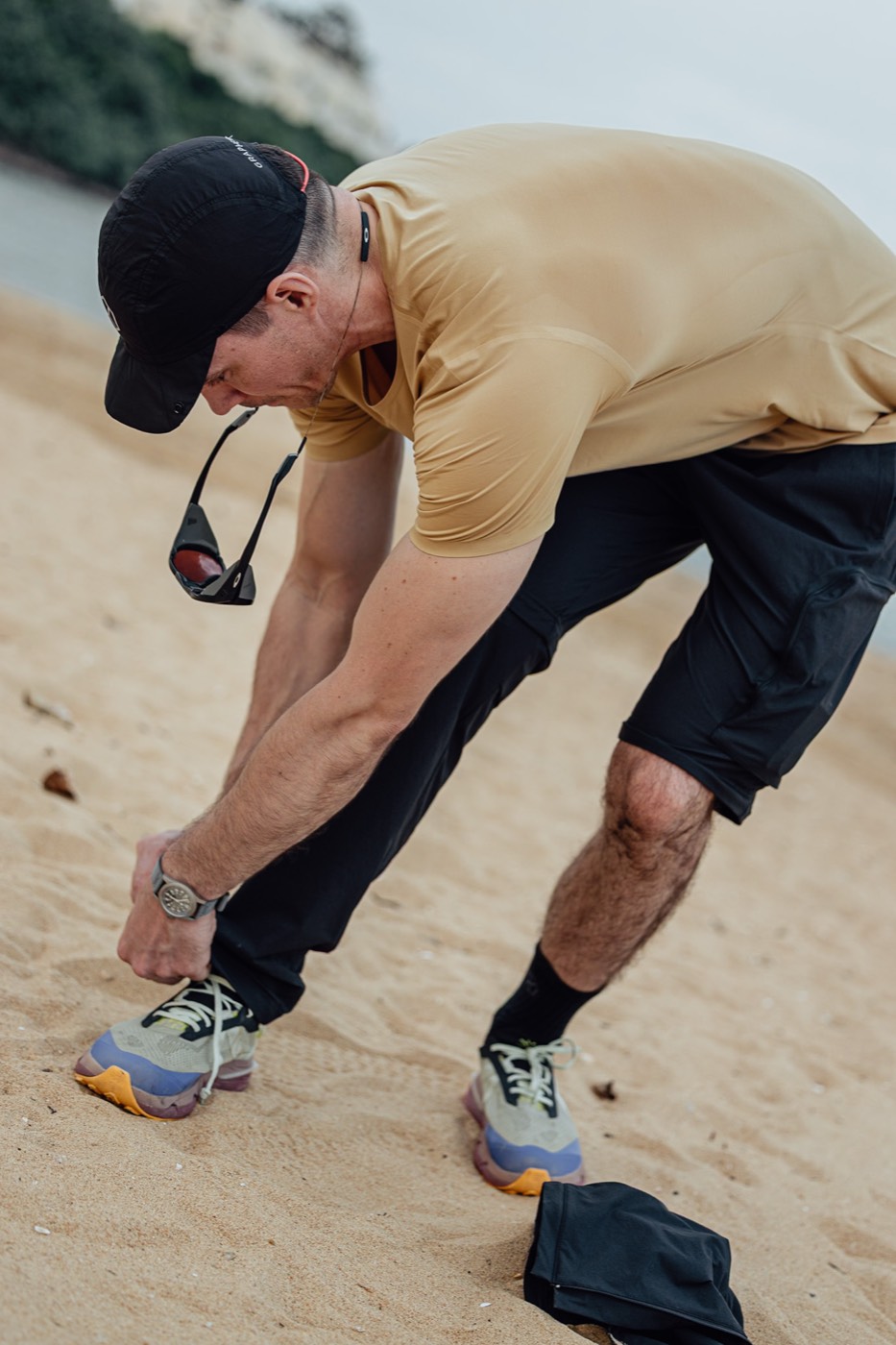 Tying a shoe on the beach with the lower legs of All Rounder Adventure zipped off.