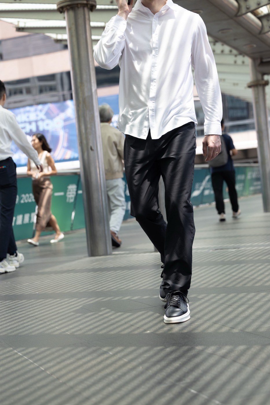 On a Hong Kong footbridge in All Rounder Urban, phone to ear.
